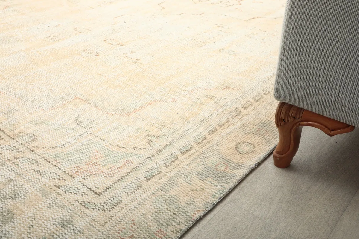 Close-up of the rug's border design next to a sofa leg, showing subtle geometric motifs