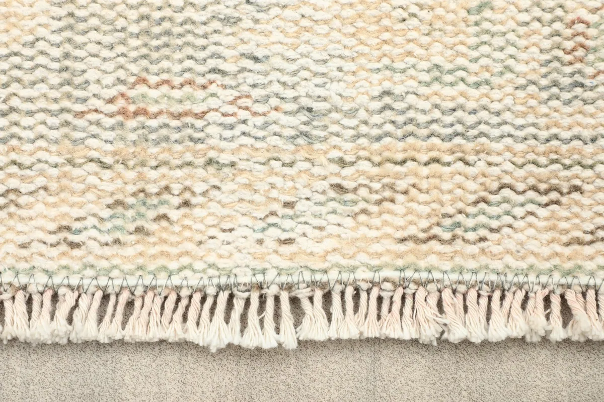 Close-up of the short, natural fringe and textured weave of the rug