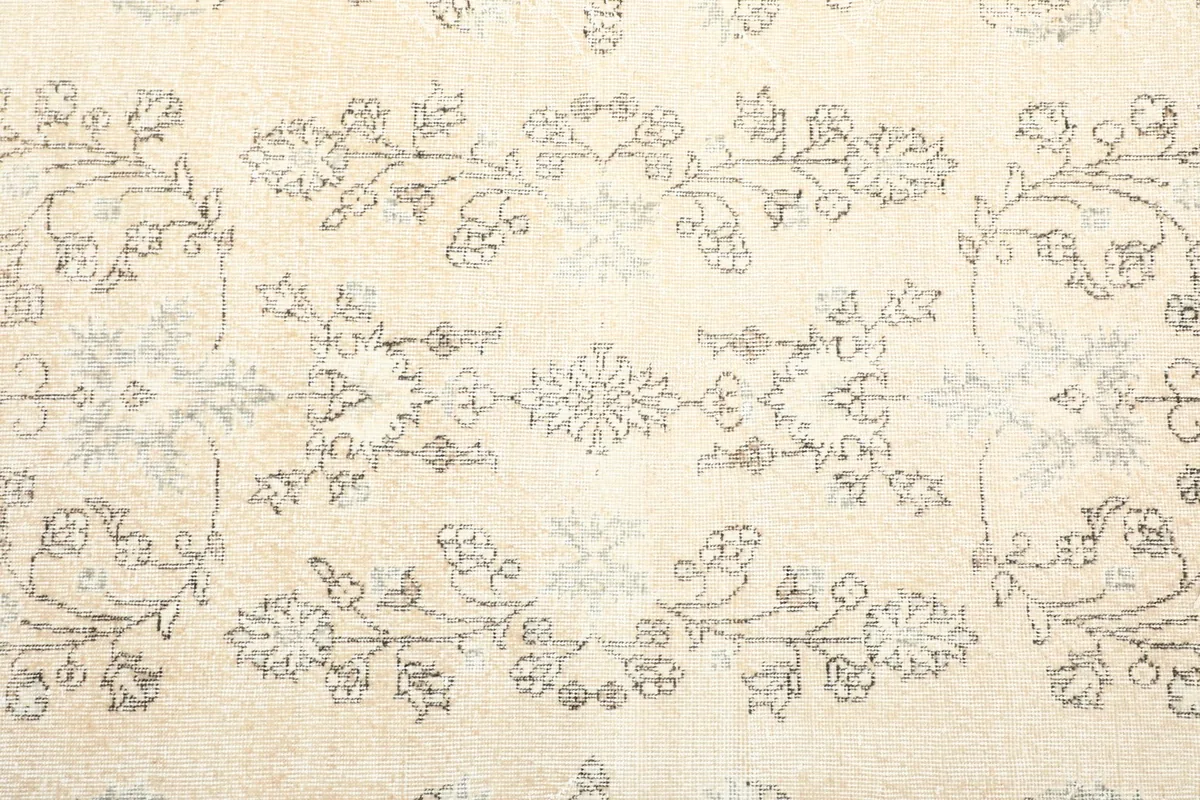 Detailed view of the central field, showcasing faded floral and geometric motifs on an ivory background