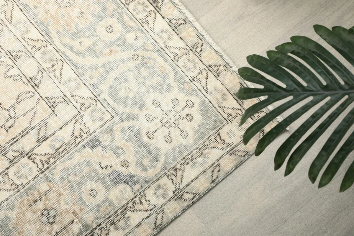 Overhead detail of a section of the rug, highlighting the soft gray border and faded patterns