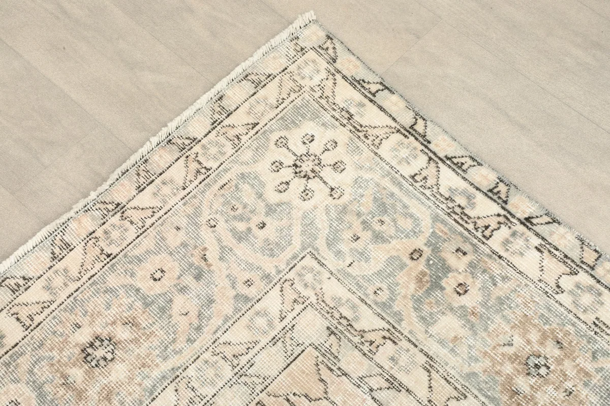 Close-up of the corner and border design, revealing subtle gray and tan intricate patterns