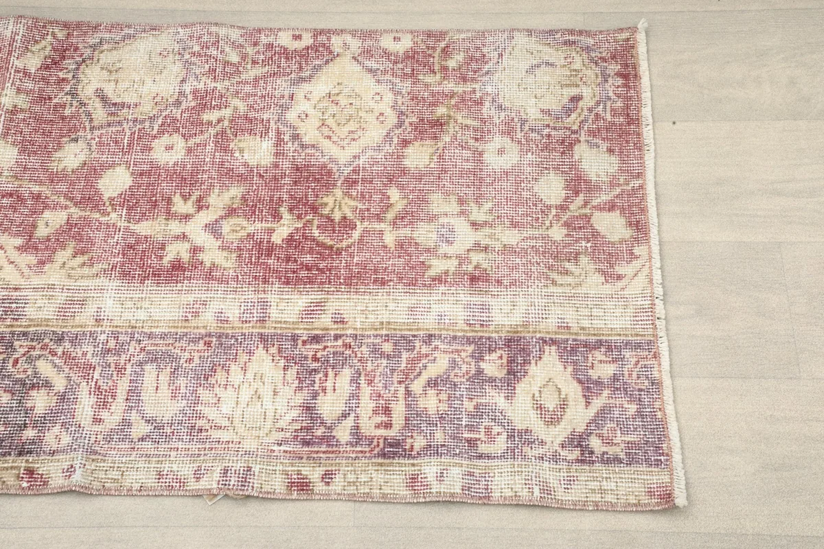 Close-up of the patchwork seam and floral motifs in rose, purple, and cream tones.