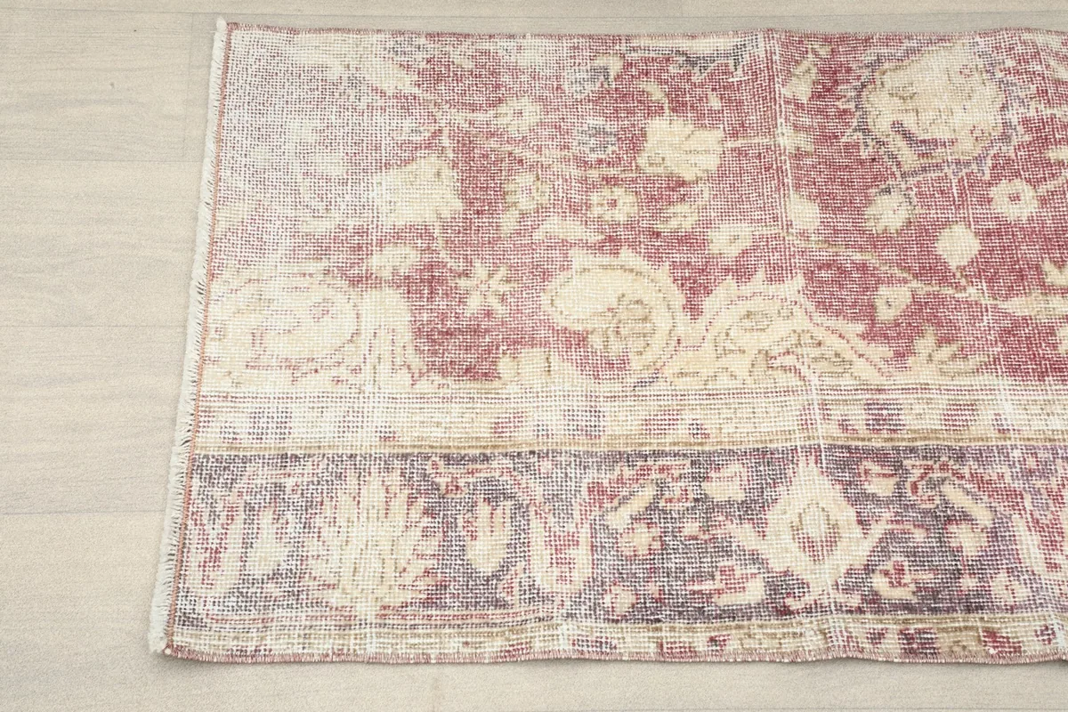 Detailed view of the rug's edge, showing faded rose and cream patterns.