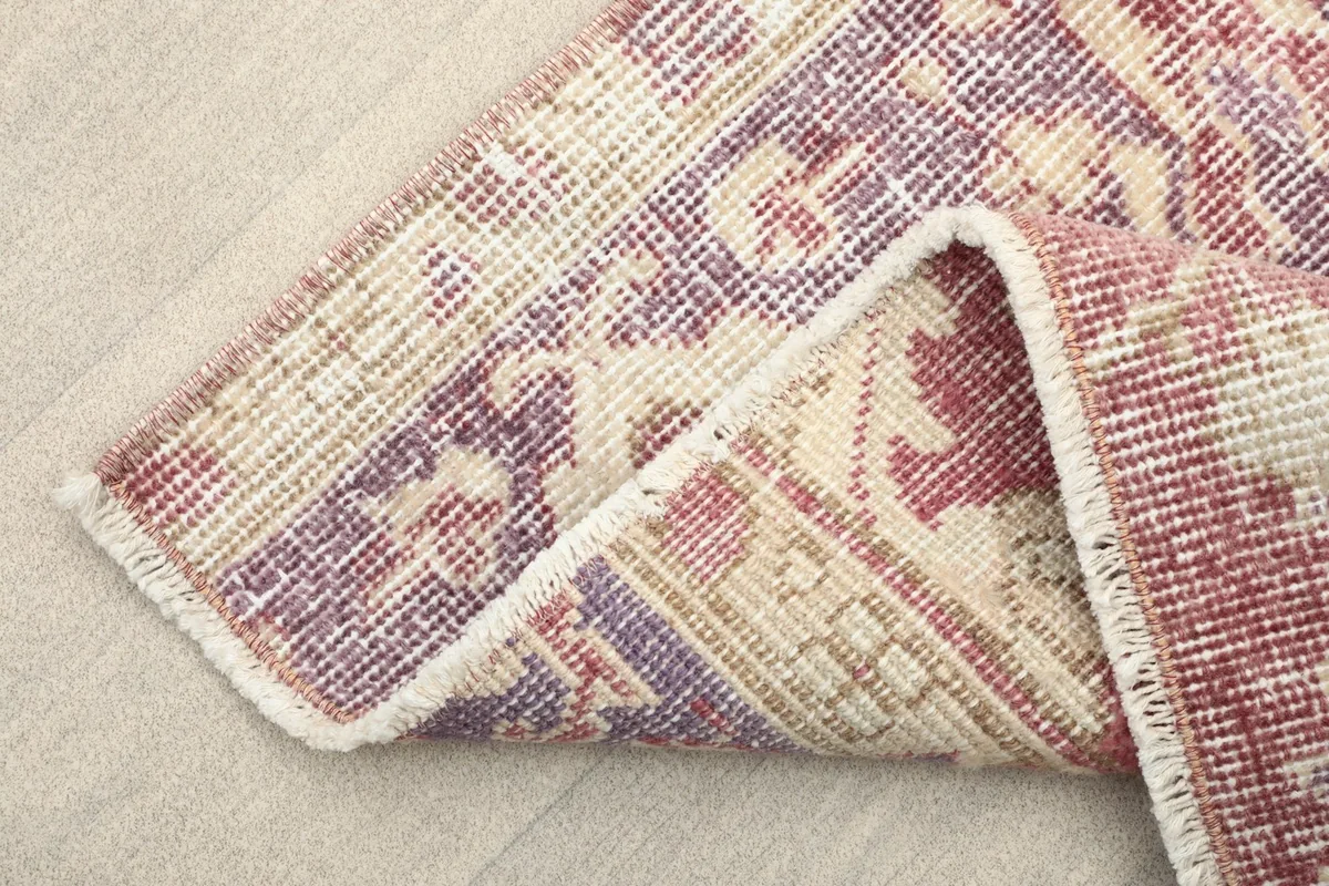 Folded corner of the rug, showing the wool pile and cotton foundation.