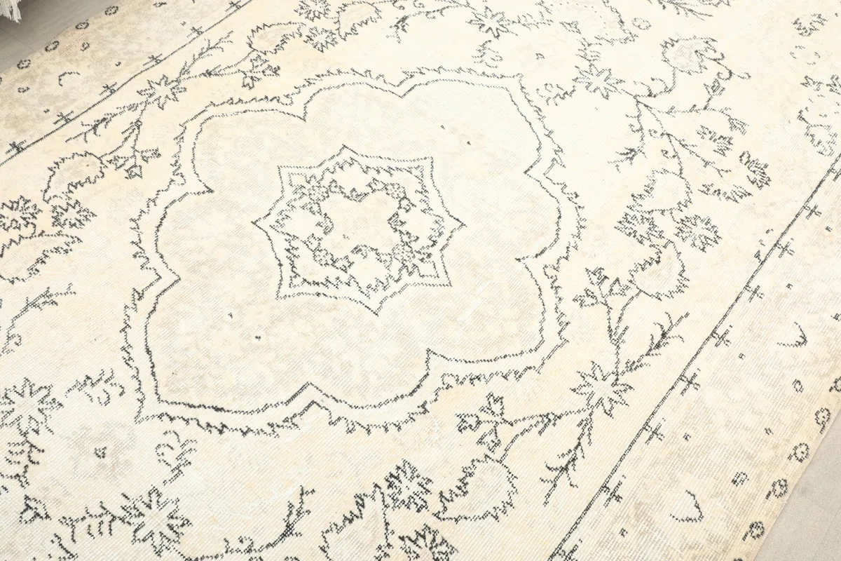 Close-up on the central medallion and surrounding floral scrollwork in charcoal on the cream background.
