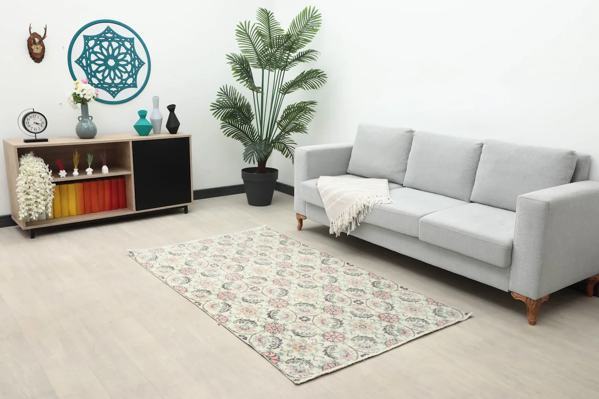 Ivory vintage rug placed in a living room space with a gray sofa and wooden console