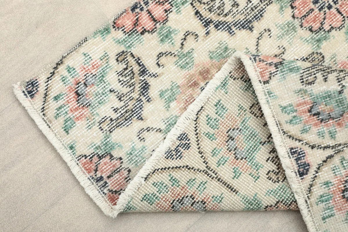 Folded corner of the rug revealing the wool pile and cotton foundation, showing the reverse side