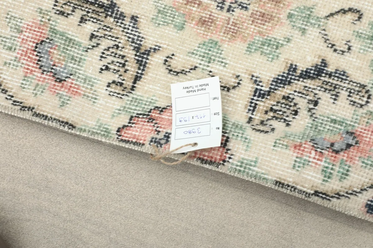 Corner of the rug with a tag displaying product information, showing the fine knotting
