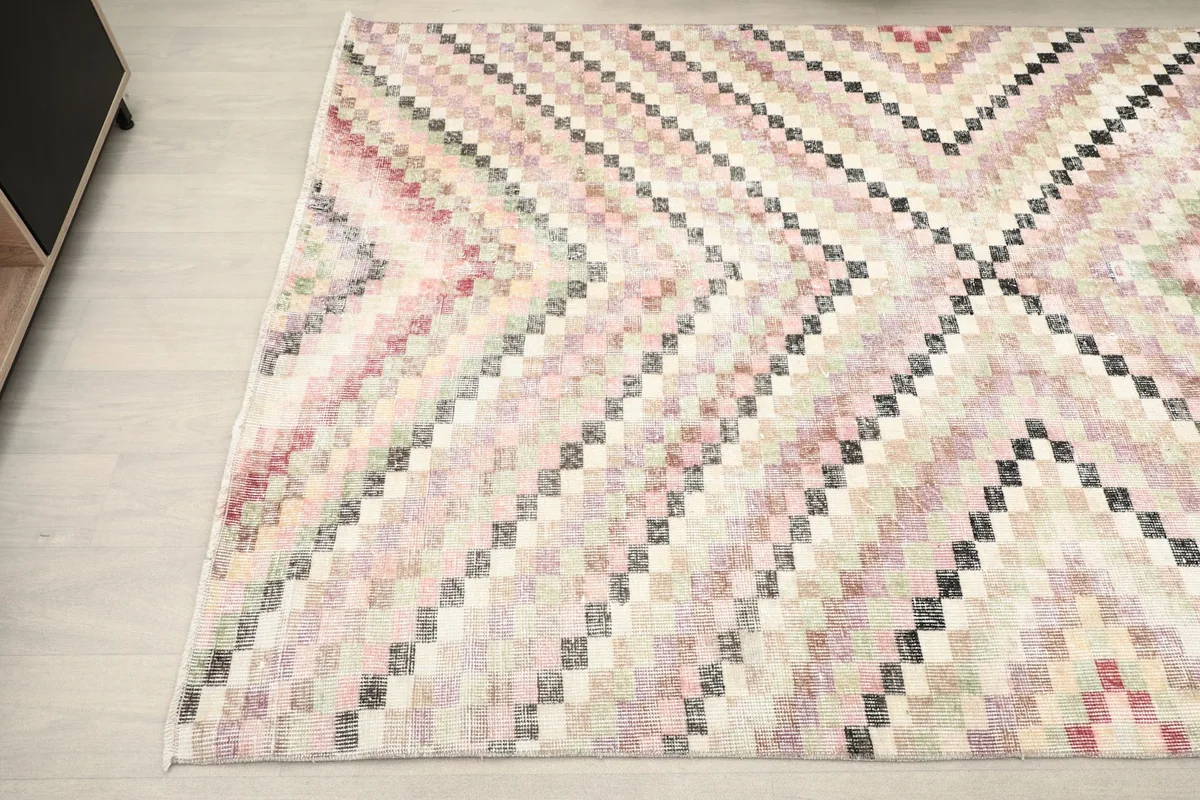 Corner view of the beige multicolor rug, showing its shape and pattern detail