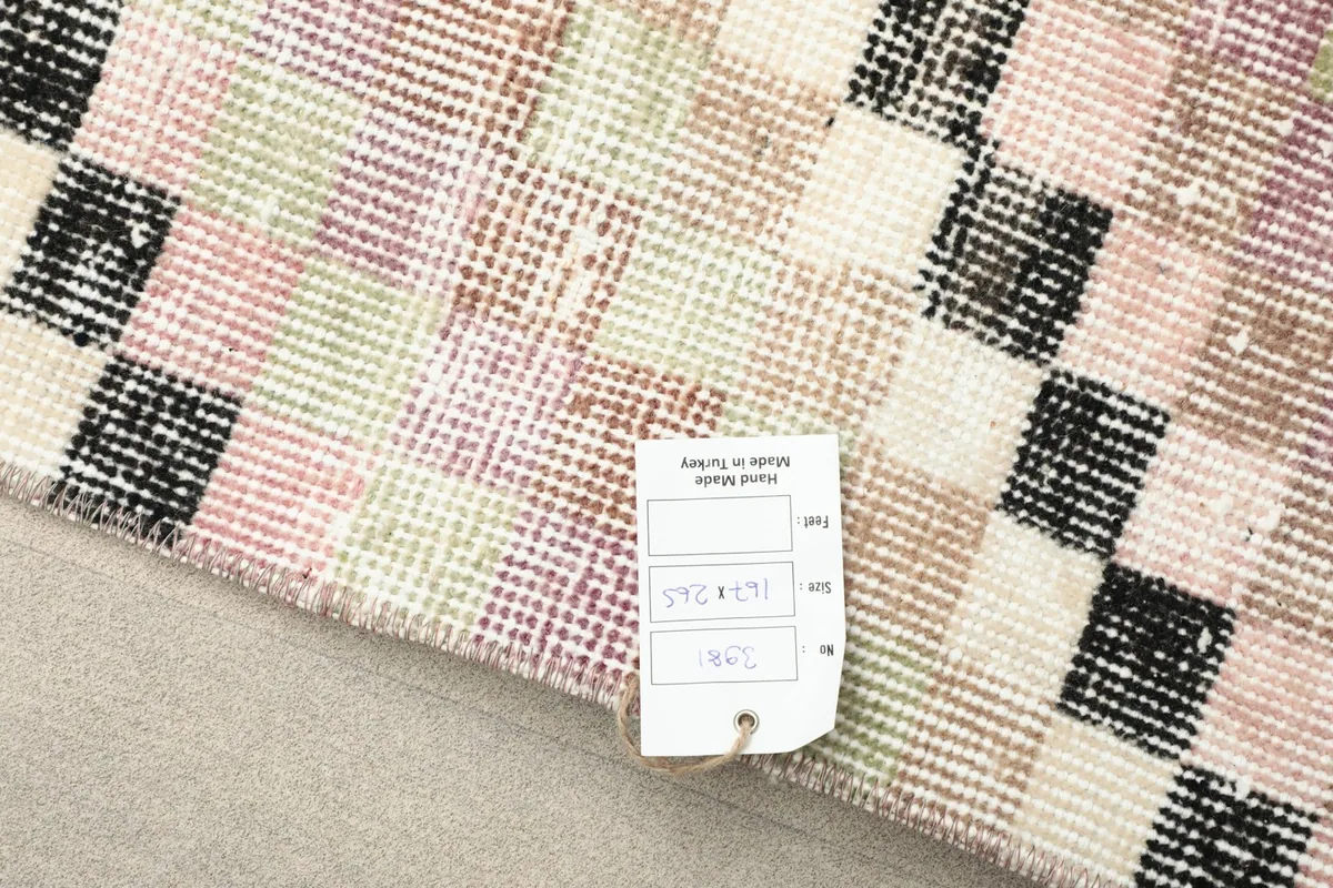 Reverse side of the rug showing the hand-knotted cotton foundation and a size tag
