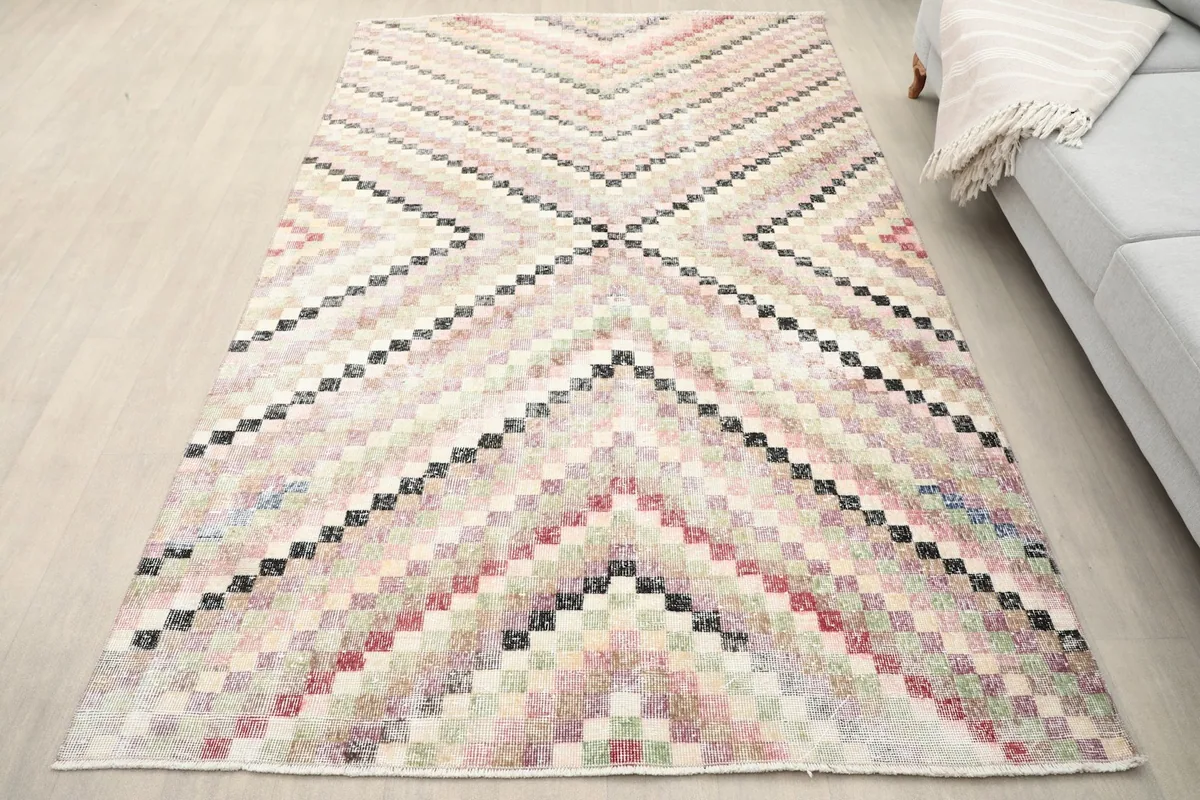Slightly angled overhead view of the beige multicolor rug on a light floor