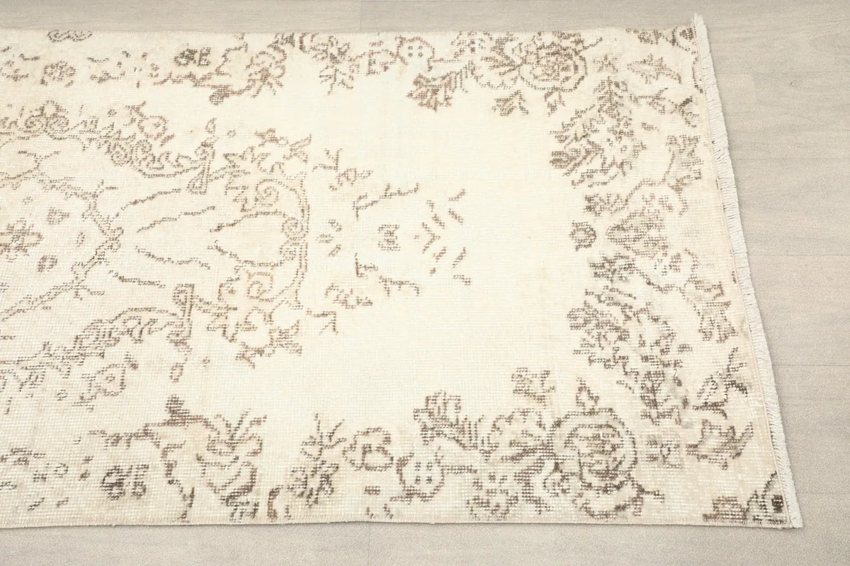 Close-up of the end border of the runner, showing the faded brown floral and leaf patterns.