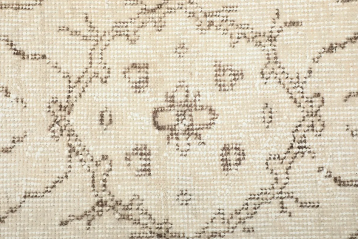 Extreme close-up of the low wool pile and hand-knotted weave, showing texture and faded colors.