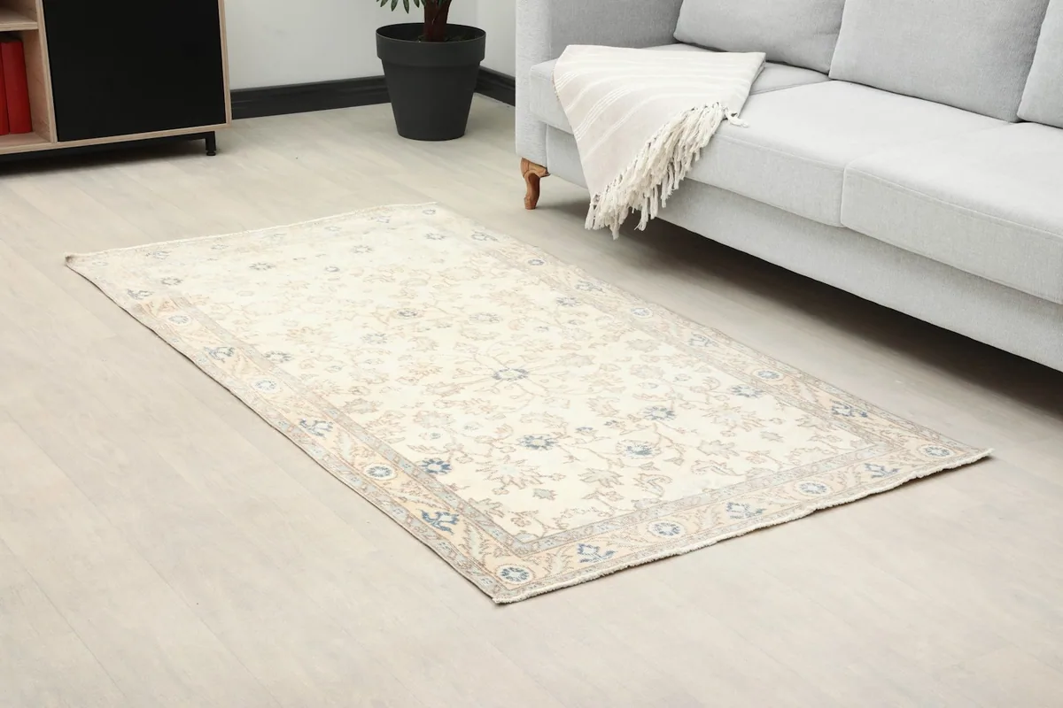 Angle view of the ivory floral rug in a living room, showing its placement near a sofa.