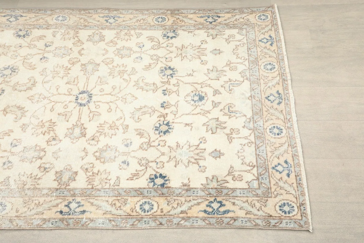 Close-up detail of the ivory field and blue and tan floral motifs with a subtle border.
