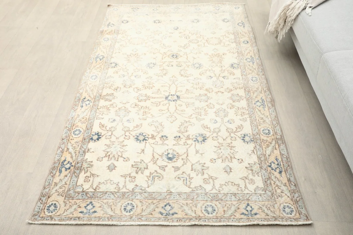 Overhead view of the small ivory rug with blue and tan floral patterns in a room setting.