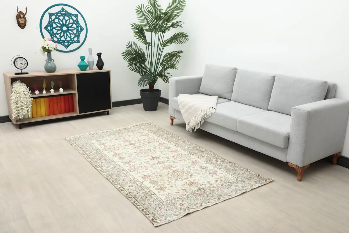 Vintage Anatolian rug displayed in a living room setting with a gray sofa and wooden cabinet