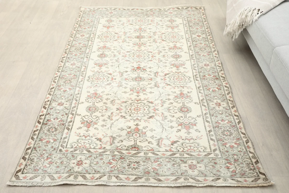 Overhead view of the ivory and rose Anatolian rug on a light wooden floor