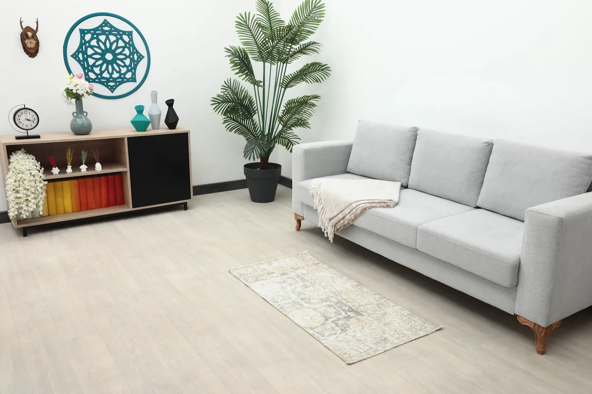Vintage beige and gray rug placed in a modern living room setting next to a sofa.