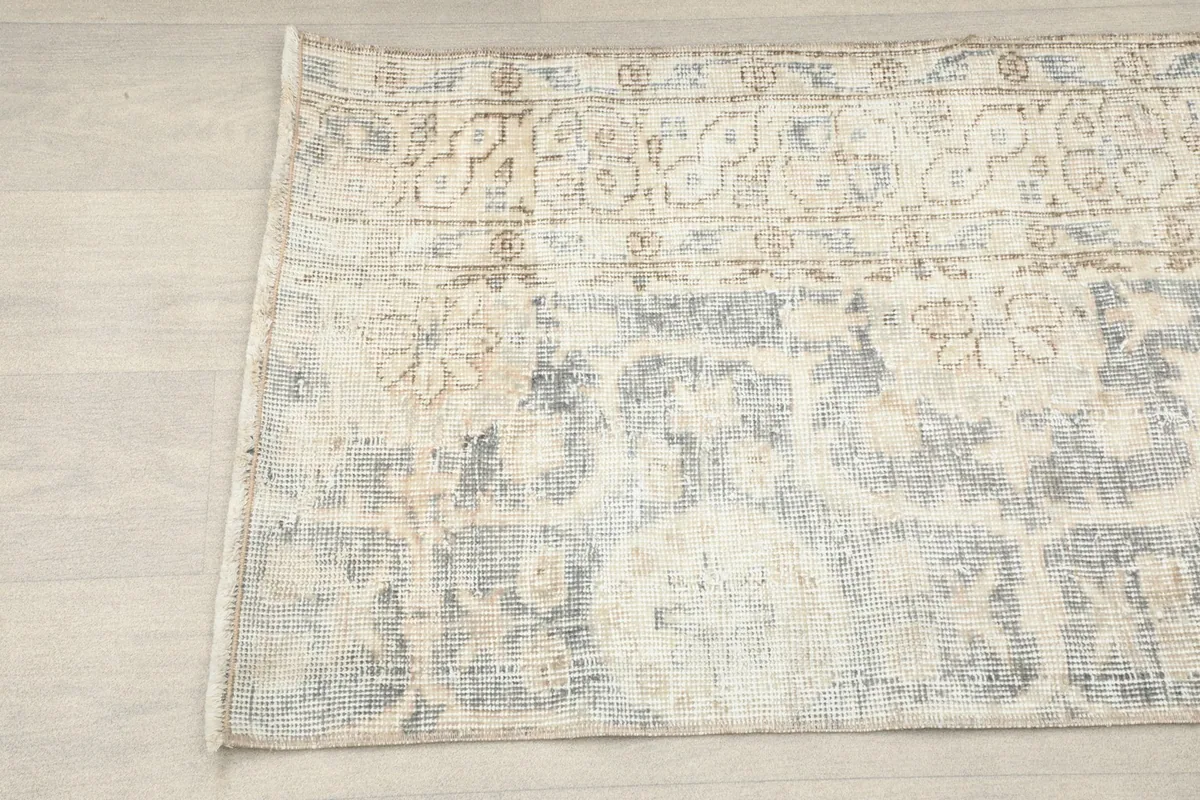 Detailed view of the rug's surface, showing areas of faded gray and beige wool pile.