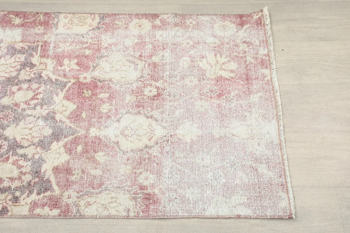 Close-up of one end of the rose and ivory rug, highlighting the faded pattern