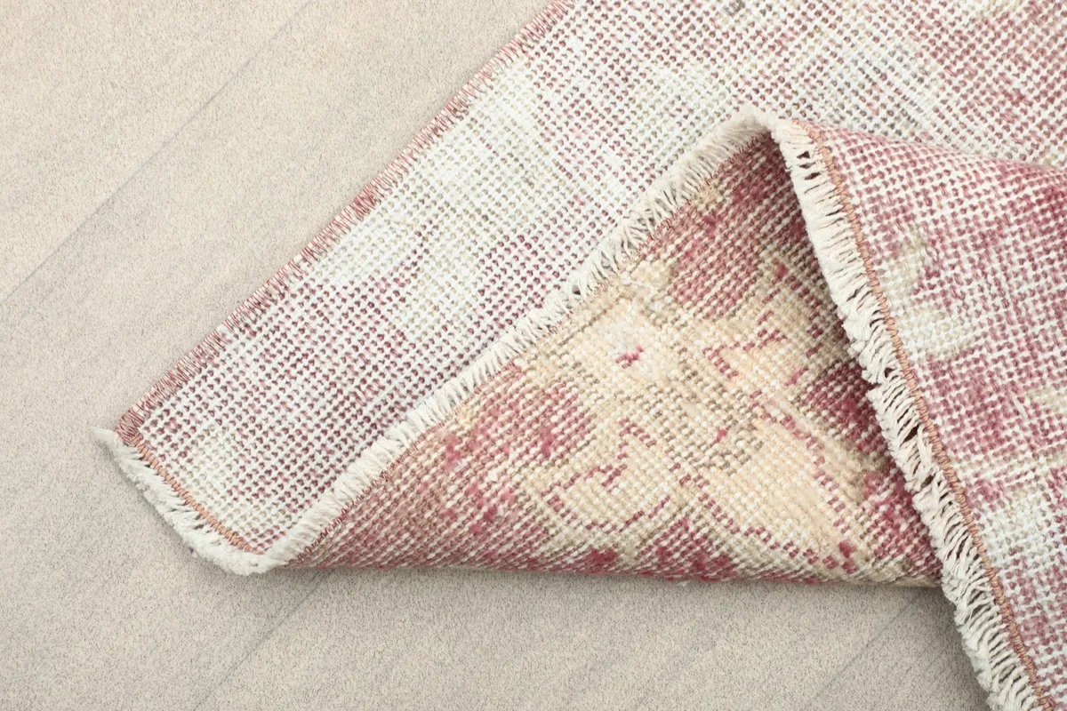 Folded corner of the rug revealing the cotton foundation and reverse side