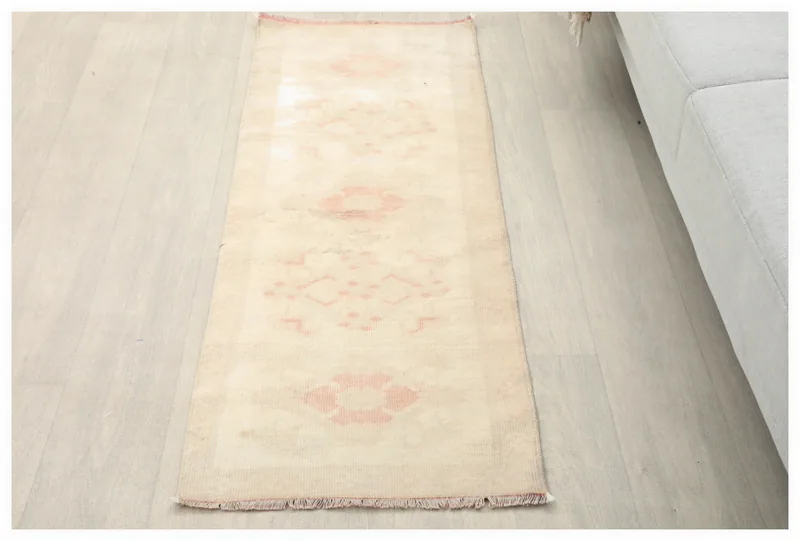 Full top view of the 1'8" x 4'8" cream and rose vintage runner rug on a light floor.