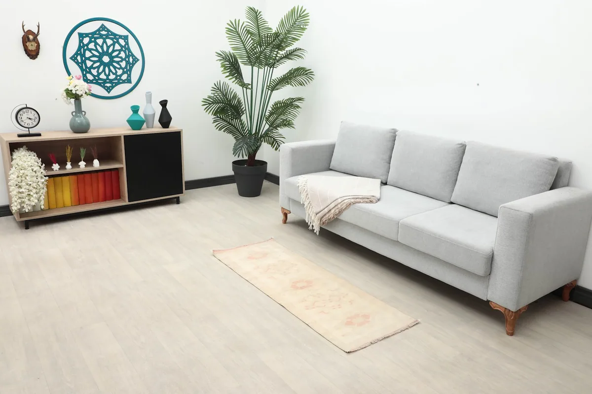 Vintage runner rug in a living room setting next to a gray sofa and wooden cabinet.