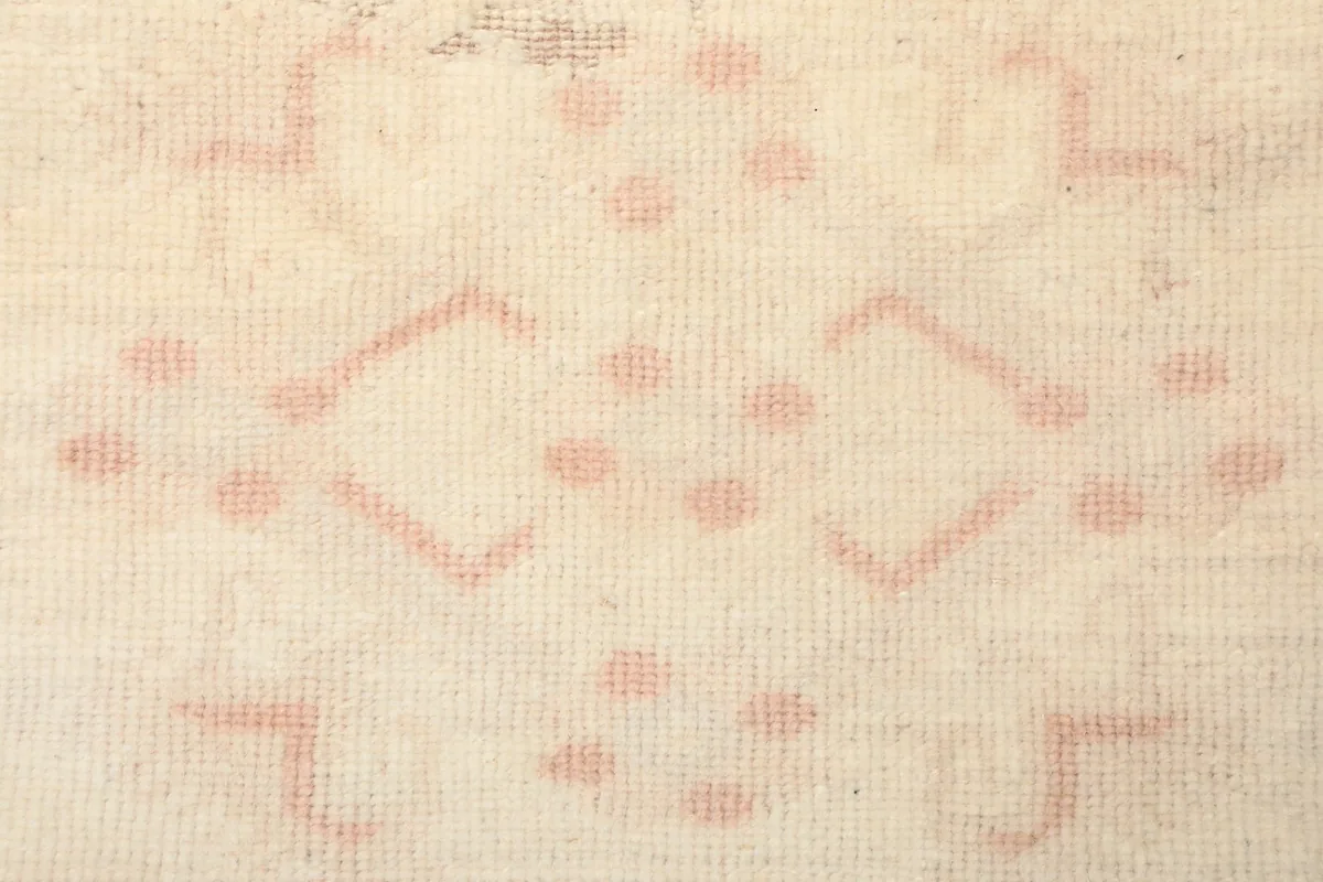 Extreme close-up of the low wool pile and the hand-knotted texture of the rug.