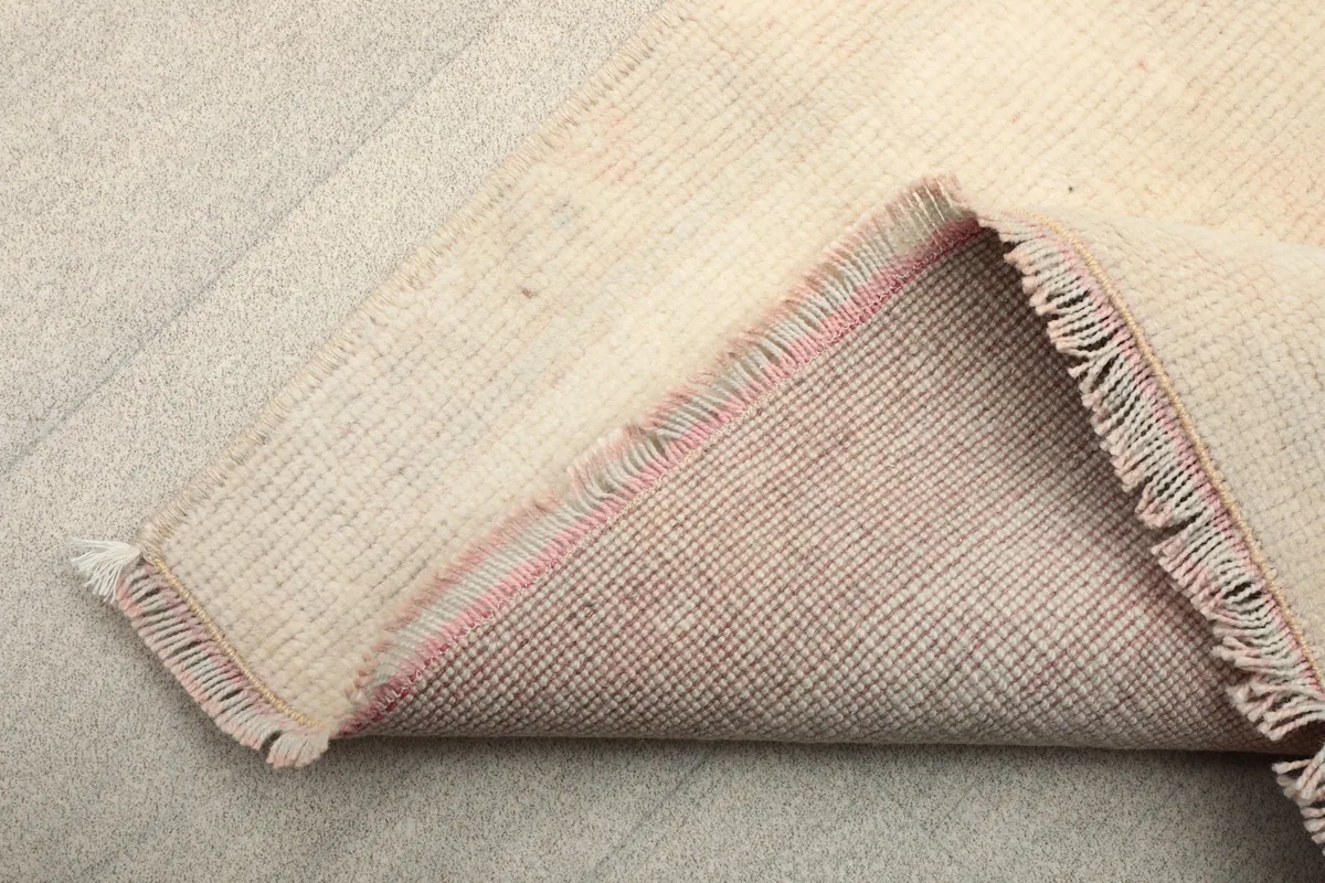 View of the back of the hand-knotted wool rug, showing the cotton foundation and fringes.