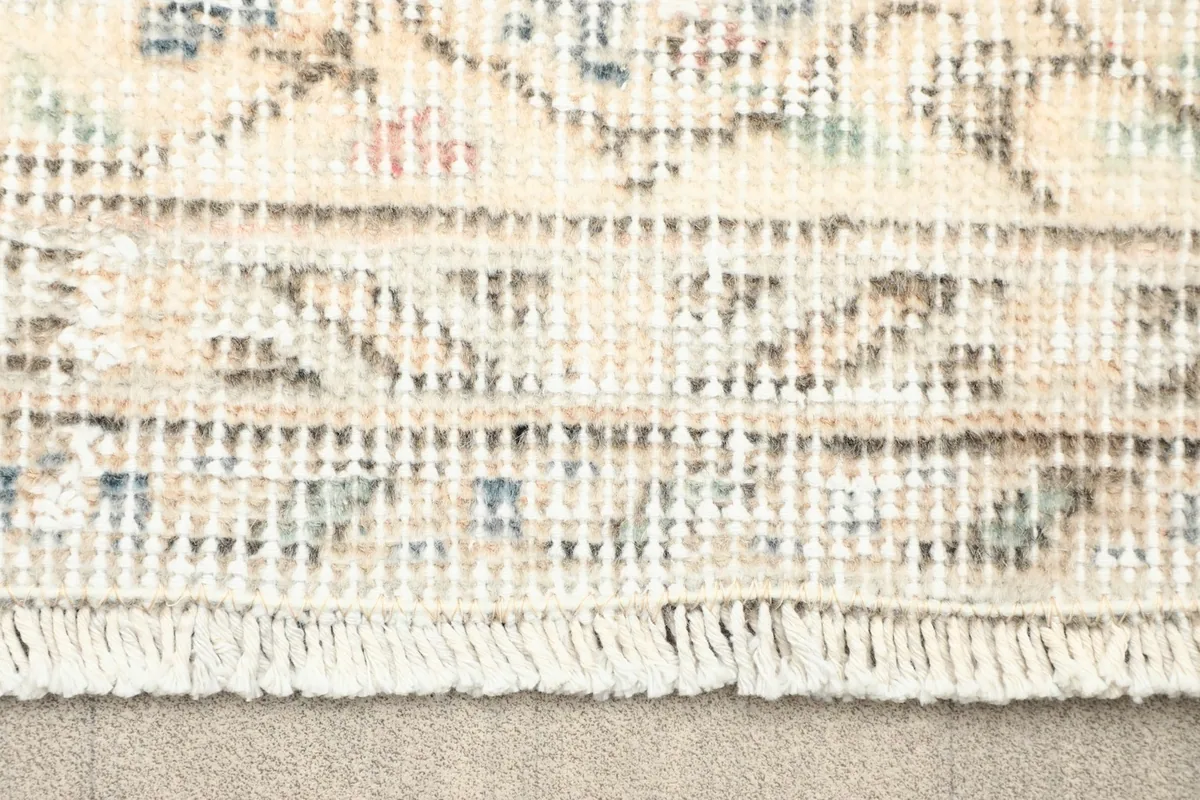 Close-up of the rug's fringe and the tightly woven edge, showing the wool pile and cotton foundation.