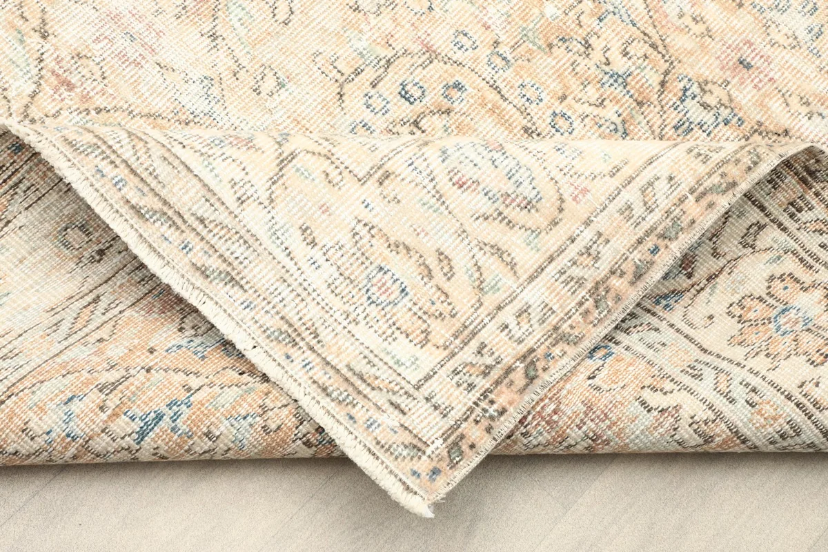 Corner of the rug folded back, revealing the reverse side and the hand-knotted construction.