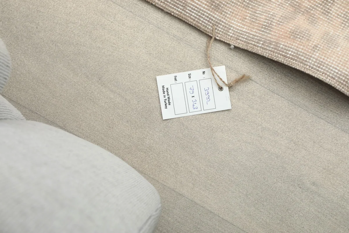 Close-up of the rug's product tag, indicating its size and origin, next to the rug on the floor.