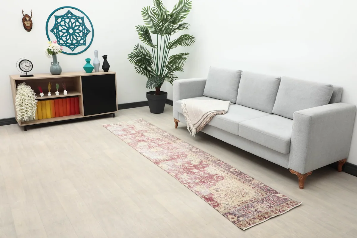 Long view of the 2x9 runner rug showcasing its length and faded rose colors in a spacious room.