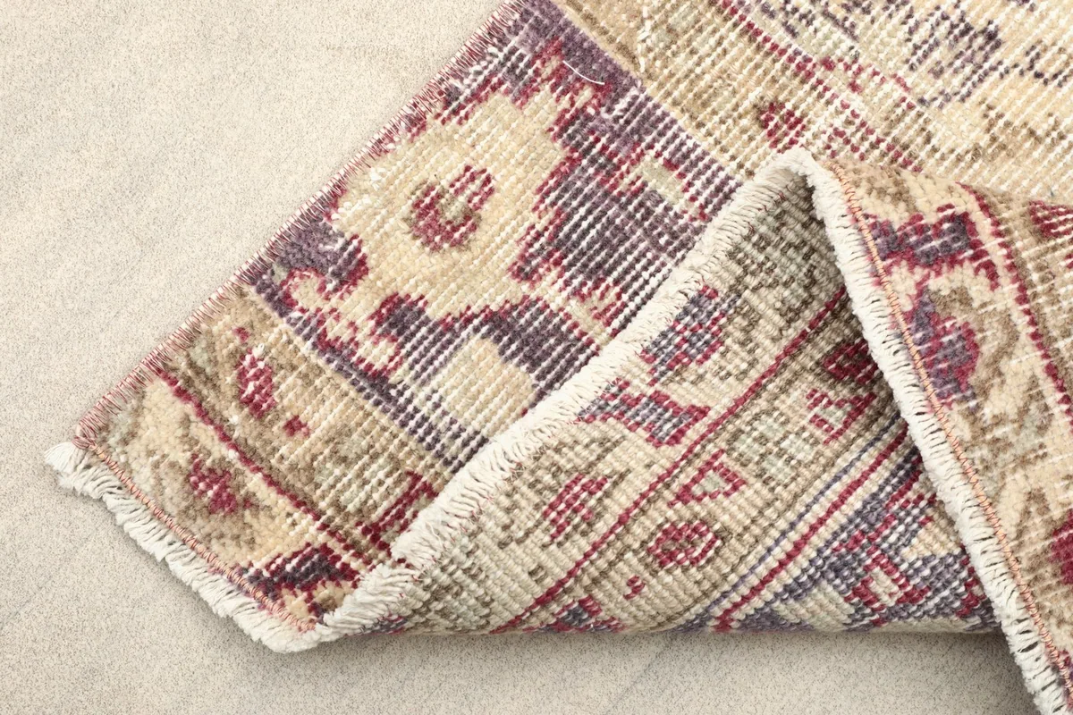 View of the back of the runner rug, showing the cotton foundation and the reverse side of the hand-knotted wool pile.