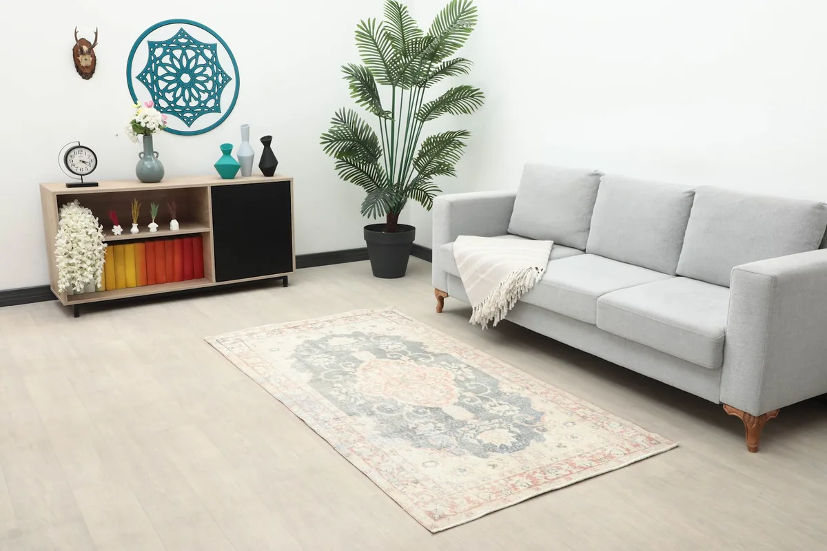 Full room view showing the small vintage rug placed in a modern living space with a gray sofa