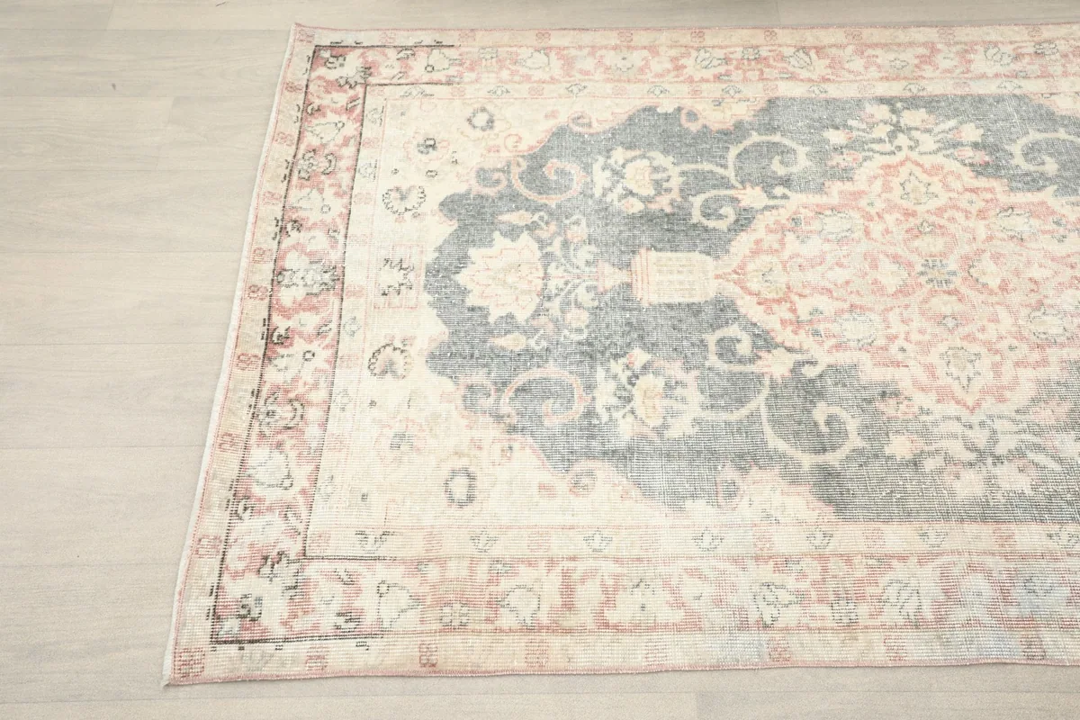 Close-up detail of the left side of the rug, showing the ivory border and charcoal medallion