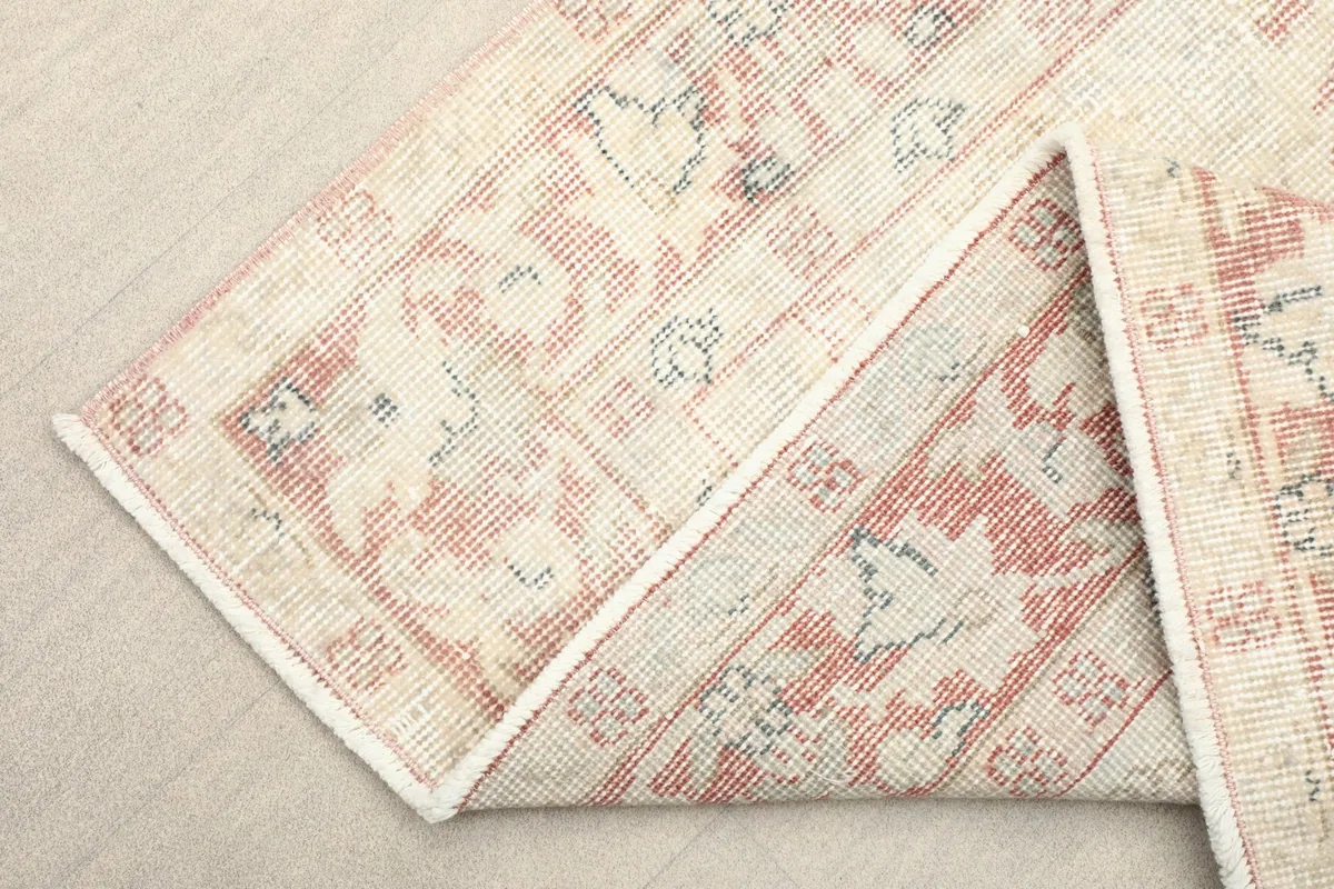Corner of the rug folded back, showing the back of the hand-knotted cotton foundation