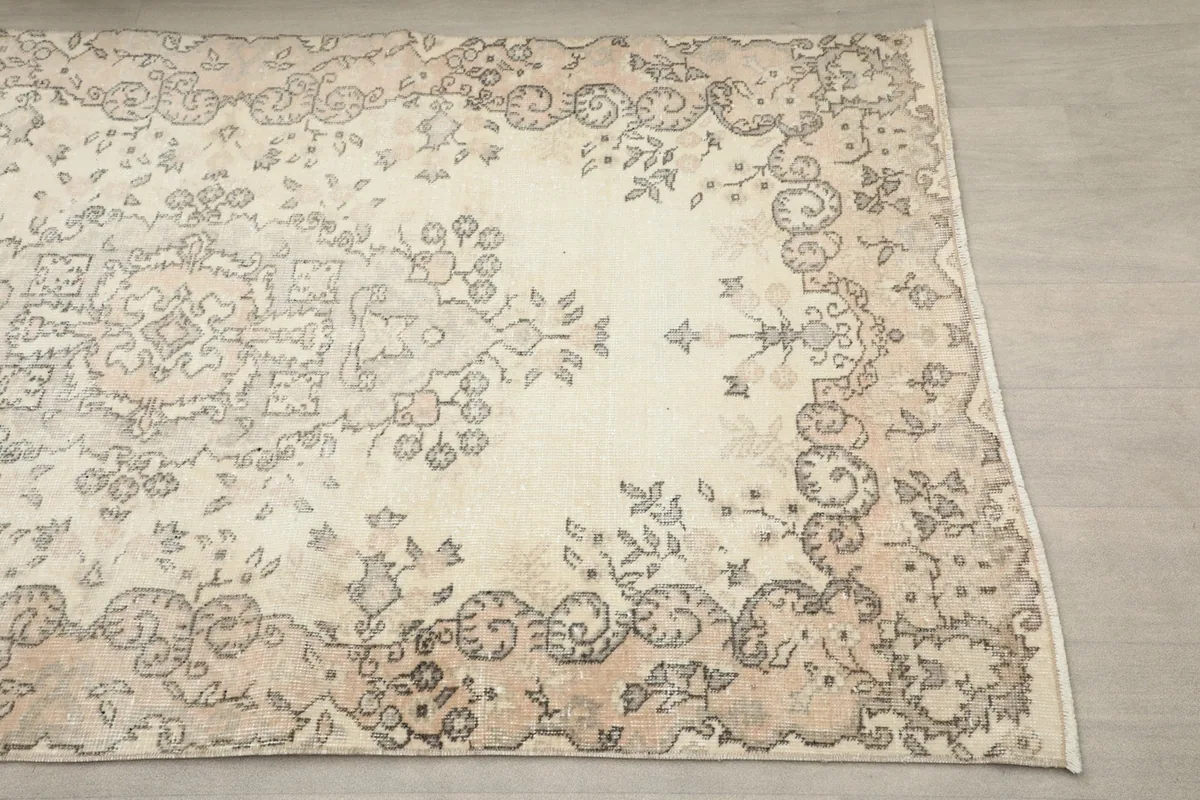 Close-up of the upper right section of the rug, showing the faded geometric and floral motifs in beige and gray.