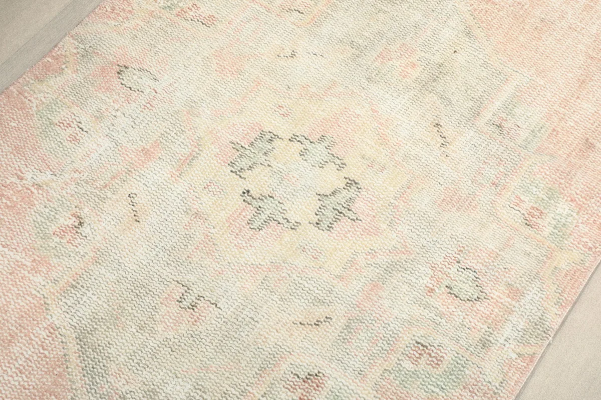 Close-up detail of the central medallion motif in beige and gray tones on the rose field