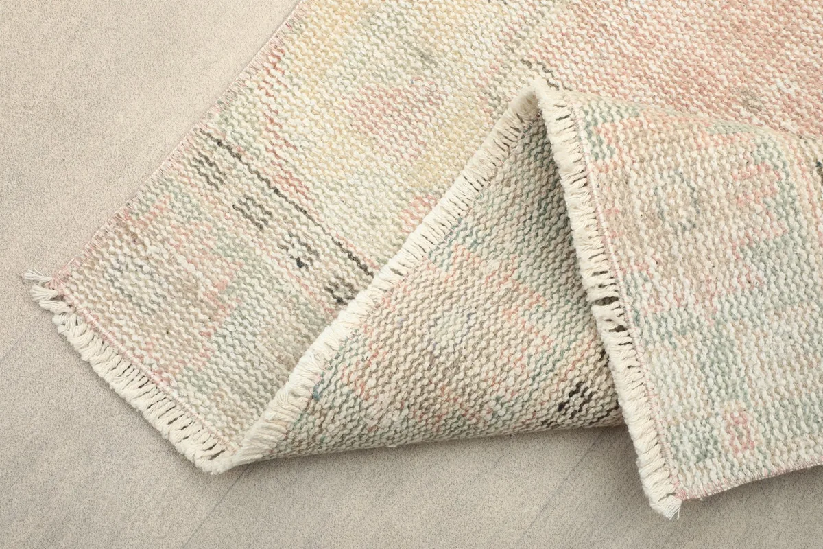 Corner of the rug folded to show the hand-knotted cotton foundation and fringe