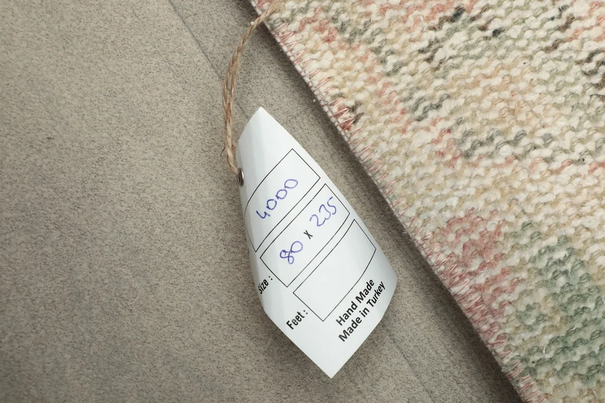 Close-up of the rug's tag, indicating its dimensions in centimeters and 'Hand Made in Turkey'