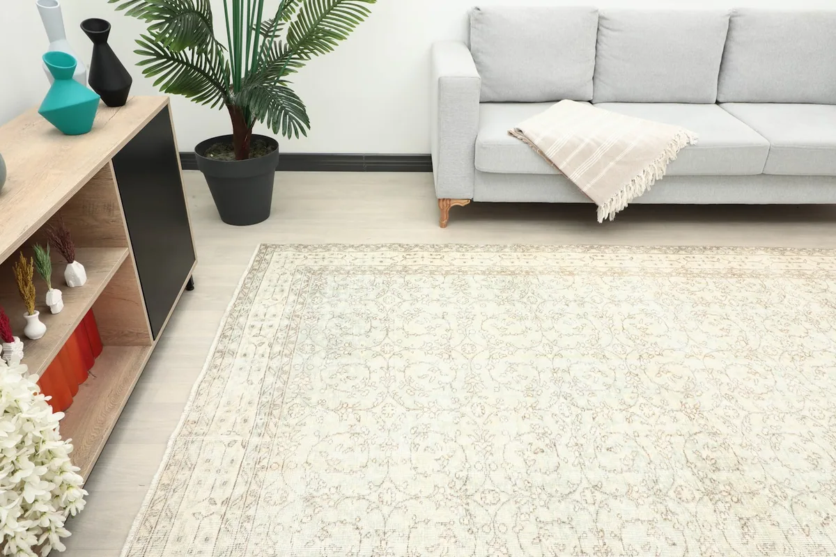 View of the cream and olive rug in a room, showing its scale next to furniture.