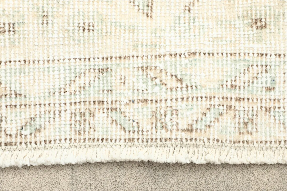 Close-up view of the rug's short fringe and a section of the border pattern.