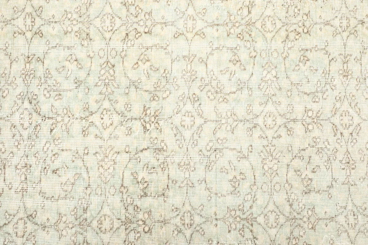Close-up of the rug's central field, revealing the faded olive and cream floral motifs.