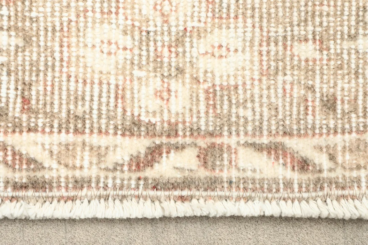 Close-up of the rug's fringe and the border pattern with cream and rust tones