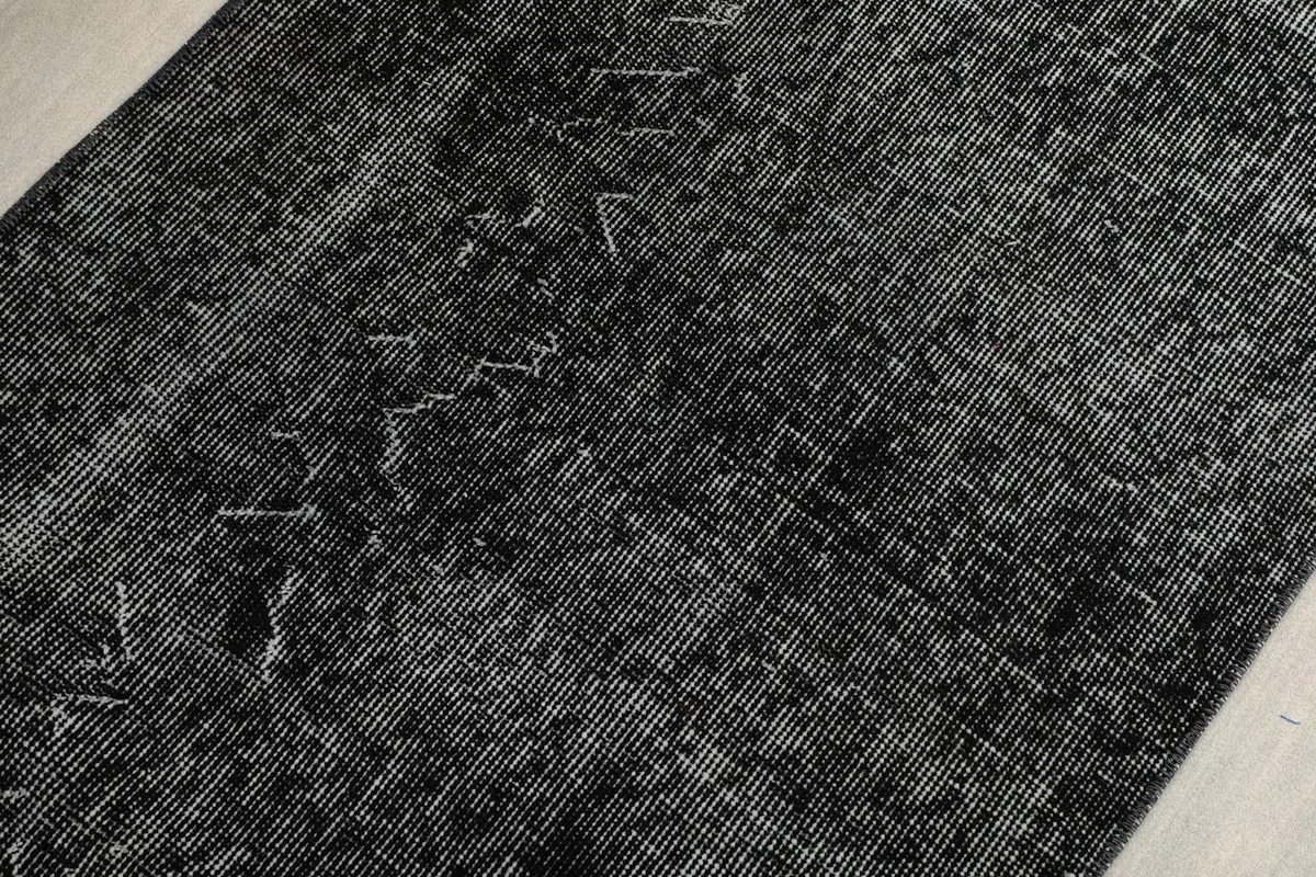 Overhead close-up showing the low wool pile and subtle charcoal and black tones
