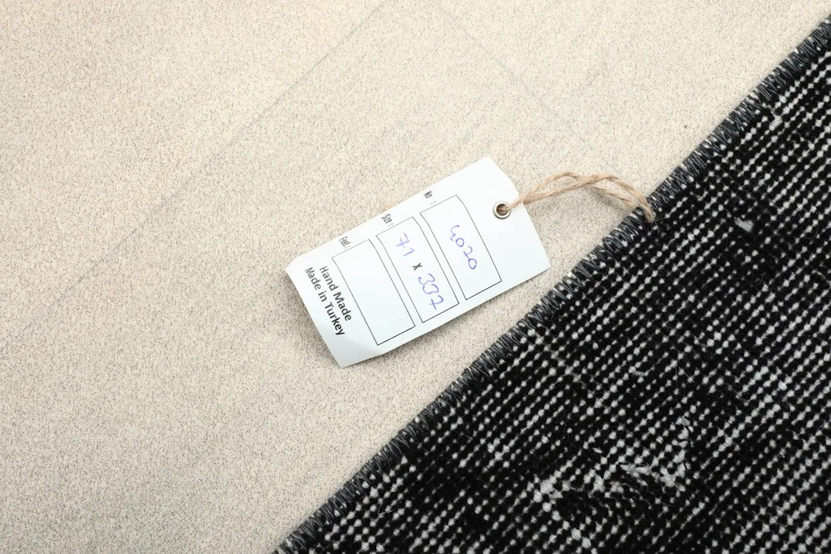 Tag showing the rug's dimensions and origin, placed on the rug's surface
