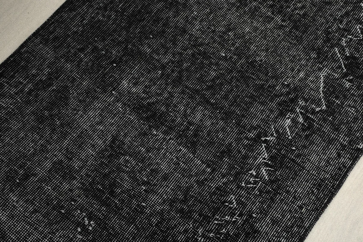 Macro shot highlighting the intricate hand-knotted texture and distressed areas of the rug