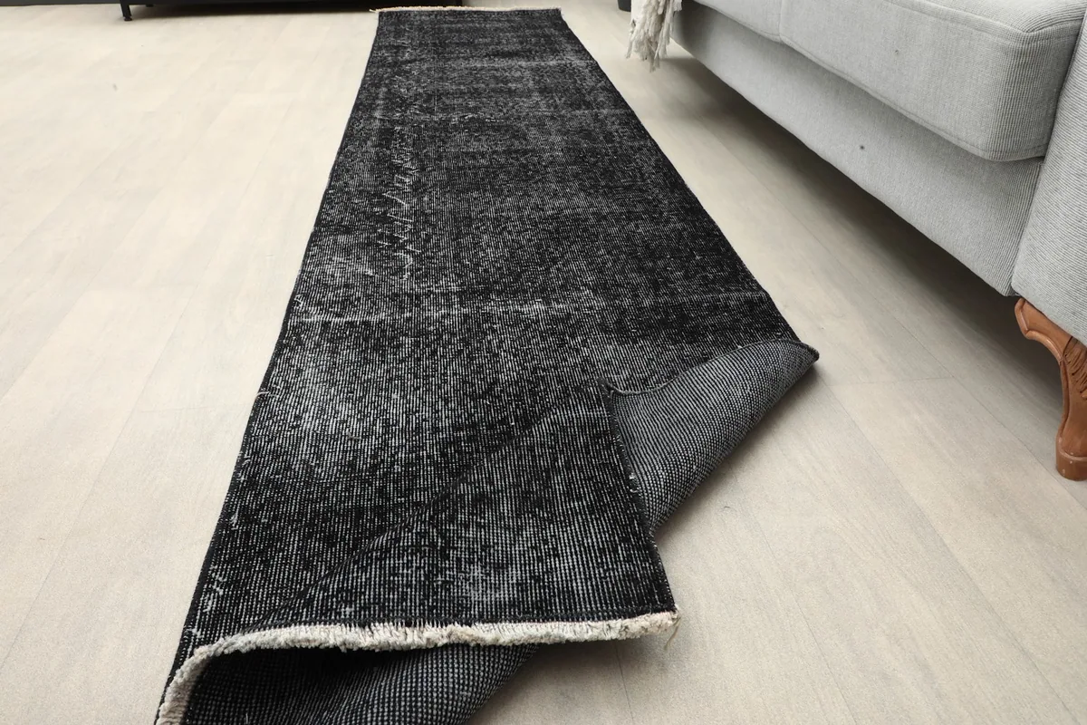 Runner rug partially rolled to show its flexibility and thickness in a room setting